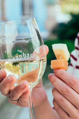 Chica con vaso de vino y tapa de queso en la mano